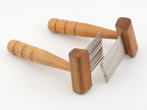 The Acorn Petite Combs by Sunrise Metal Works are displayed with metal pins extending from rectangular wooden bases, making them ideal for carding medium coarser wools. The handles are ergonomically shaped for easy gripping and set at an angle to the base. Positioned on a white background, these tools are essential for fiber spinning enthusiasts.