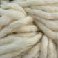 Close-up of thick, soft, white Malabrigo Rasta yarn from Malabrigo Yarn. The strands are loosely twisted together, showcasing the fluffy, textured fibers. This super bulky yarn appears smooth and plush, perfect for knitting or other quick-to-knit projects.