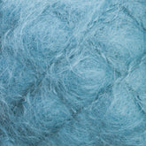 Close-up of the Victorian Brushed Mohair Yarn by Caledonian Dye Works reveals a soft and fluffy, pale blue material with a fibrous texture. The luxurious mohair fibers are thin and intertwined, creating an intricate and delicate pattern that resembles a nest or cloud of wispy threads.