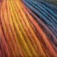 Close-up of Louisa Harding Amitola Grande yarn from Knitting Fever / Euro Yarns, showcasing a variegated, worsted weight blend that transitions beautifully from yellow to orange, red, and blue. The textured fibers exhibit a soft and woolly appearance with a touch of silk, creating a visually appealing and cozy effect.