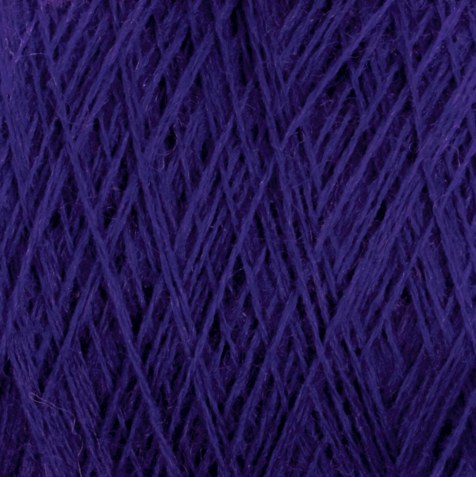 Close-up image of a skein of purple JaggerSpun Maine Line 2/20 Yarn | Large Cone by Jagger Brothers, Inc. The strands are tightly intertwined, creating a textured pattern that highlights the rich, vibrant hue of the worsted spun yarns.