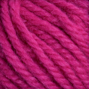 Close-up of multiple strands of bright magenta Halcyon Yarn Classic Rug Wool by Caledonian Dye Works, showcasing the texture and fiber detail. The yarn is thick and appears soft, with some visible fuzziness. Ideal for rug weavers, the hand-dye process enhances its vivid color. The strands are loosely coiled together.