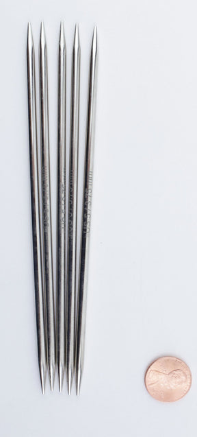 Five Nova Platina Double-Point Knitting Needles by Accessories Unlimited are arranged side by side on a white background. Each slender needle, crafted from high-quality chrome, features pointed tips on both ends. A copper penny lies next to the needles for scale.