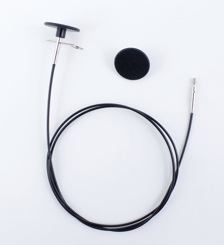 A coiled black Interchangeable Circular Needle Cord for Dreamz and Nova by Accessories Unlimited, featuring a metal tip, is attached to a small black circular device with a pin. An additional black circular component, resembling those used in knitting accessories, is placed separately alongside the cord. The objects are arranged on a plain white background.