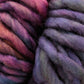 Close-up image of thick, multicolored Malabrigo Yarn's Malabrigo Rasta with hues of purple, pink, and blue. The texture appears soft and cozy, showcasing the fiber's woven and fluffy strands. This super bulky yarn is perfect for quick-to-knit projects.