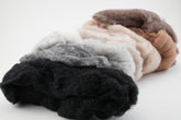 A close-up image showcases several tufts from the Harrisville Fiber Batts Collection by Halcyon Yarn in different natural colors, including white, gray, brown, and black, laying on a plain white surface. The texture of the fiber is visible, highlighting its soft and fluffy appearance—perfect for felting projects.