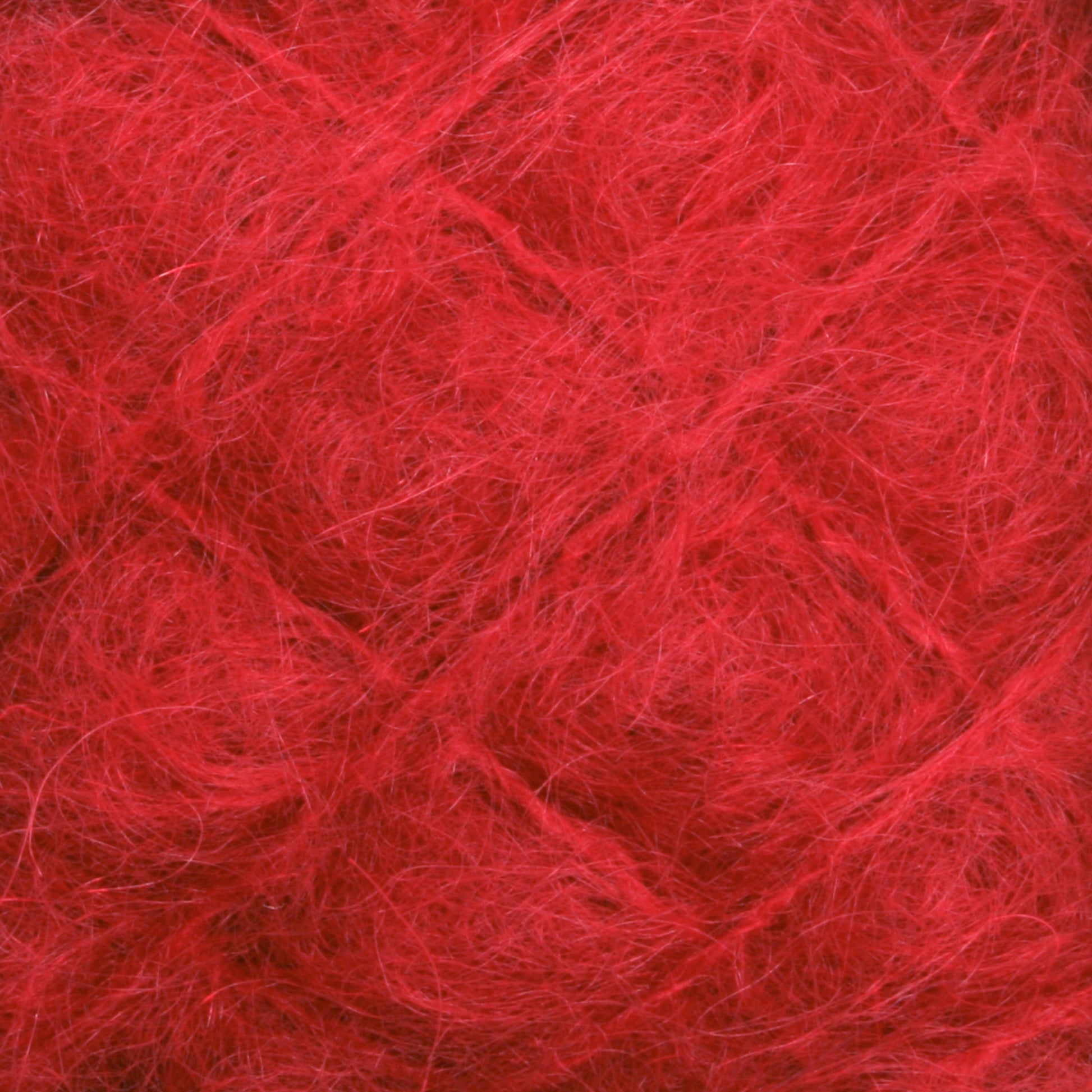 Close-up of the vibrant red Victorian Brushed Mohair Yarn by Caledonian Dye Works, highlighting its detailed fibrous texture. The strands intertwine loosely, creating a soft, fuzzy appearance with delicate wisps of luxurious mohair fibers extending in various directions.