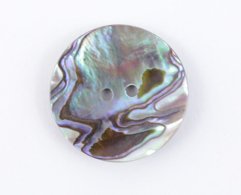 Close-up of a round, two-hole Skacel Mexican Abalone Button. The button features an iridescent surface with swirling patterns in shades of purple, green, and blue, adding a touch of elegance to finished sweaters.