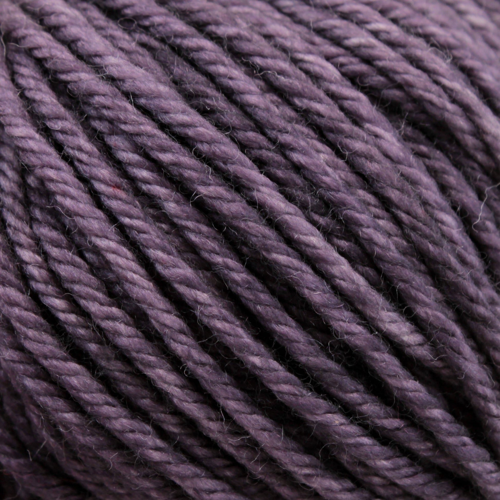 Close-up view of a ball of purple Malabrigo Rios yarn from Malabrigo Yarn, showcasing its tightly spun fibers and slightly textured surface. The yarn appears soft, perfect for knitting or crocheting projects.