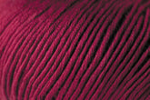 A close-up image of tightly wound, deep burgundy Jo Sharp Soho Summer DK Cotton Yarn from Kingfisher Yarn & Fibre. The texture of the yarn is detailed, with individual strands visible, showcasing the fibers in a neat, orderly pattern. The rich color and smooth surface highlight the quality of this lightweight cotton yarn perfect for summer projects.