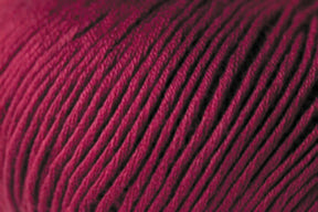 A close-up image of tightly wound, deep burgundy Jo Sharp Soho Summer DK Cotton Yarn from Kingfisher Yarn & Fibre. The texture of the yarn is detailed, with individual strands visible, showcasing the fibers in a neat, orderly pattern. The rich color and smooth surface highlight the quality of this lightweight cotton yarn perfect for summer projects.