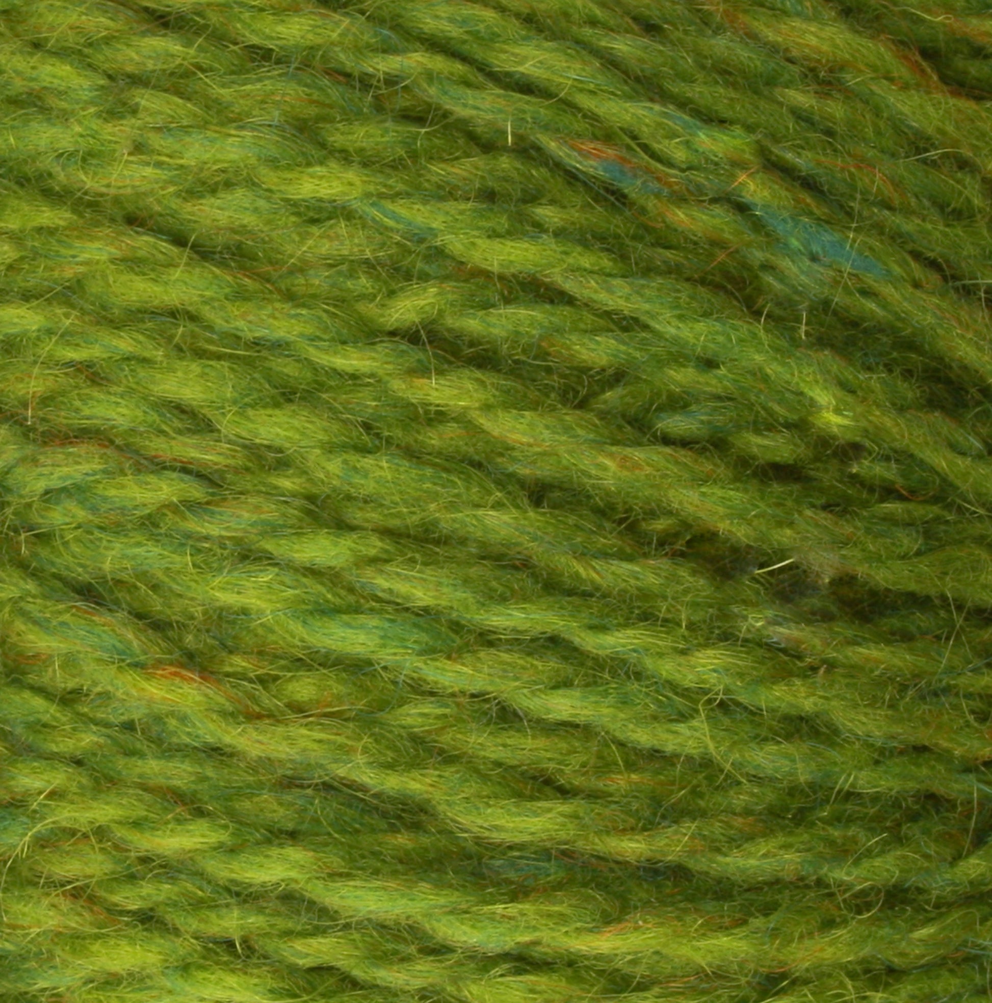 Close-up image of green Harrisville Designs Peace Fleece Yarn fibers, showing a texture with multiple intertwined strands. The wool and mohair blend has subtle variations in color, ranging from light to dark green, creating a rich and soft appearance.