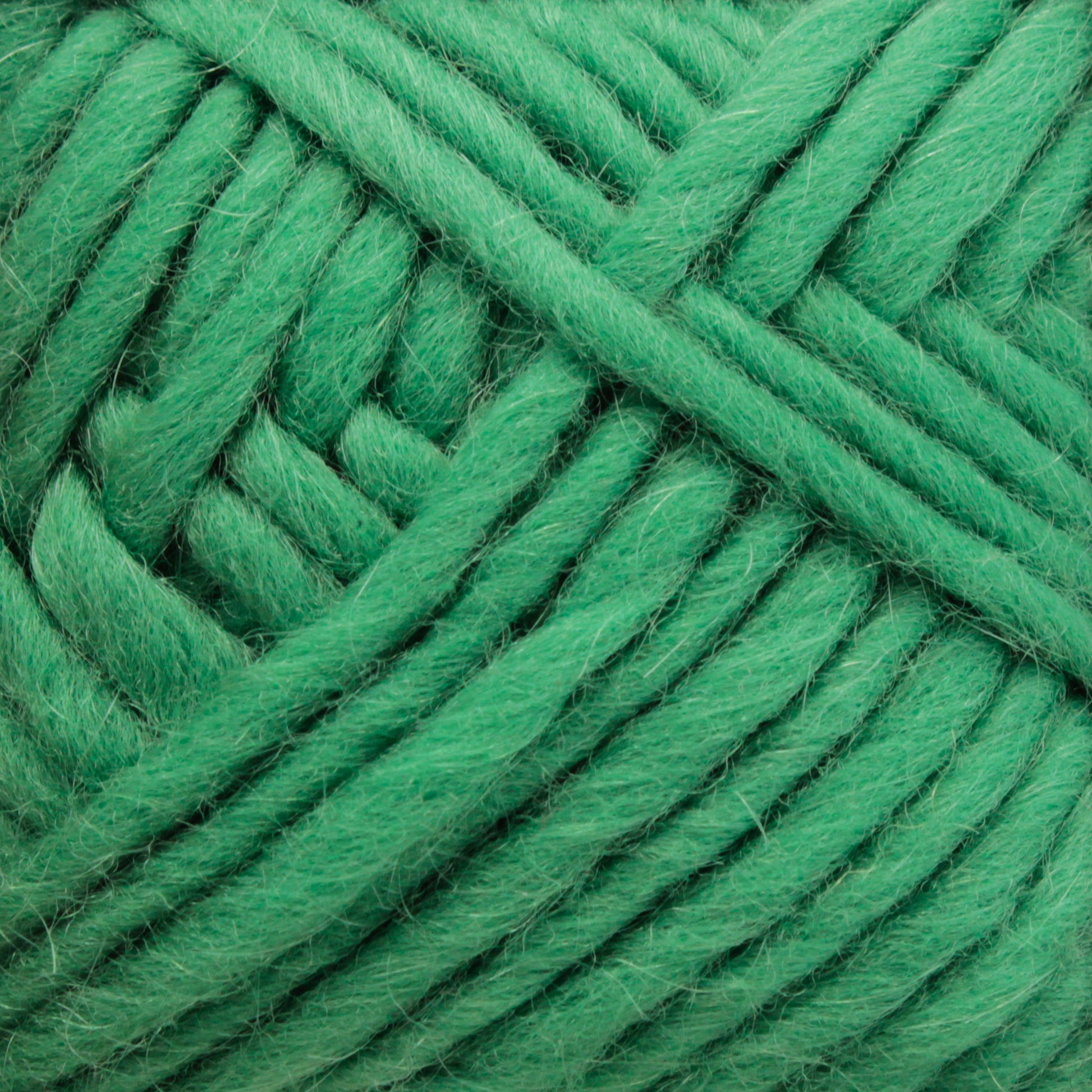 Close-up of Lamb's Pride Bulky Yarn in green, produced by Brown Sheep, showcasing its soft, thick, and slightly fuzzy texture. The yarn is tightly wound in an overlapping pattern, making it ideal for knitters and crocheters crafting cozy Icelandic sweaters.