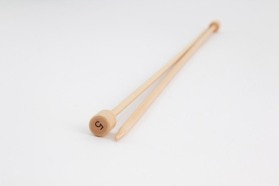 A pair of Bamboo Single-Point Knitting Needles, 12" from Accessories Unlimited is laid diagonally on a plain white background. One needle has a rounded end while the other tapers to a point, with one marked with the number 5 on its flat end. Each needle boasts a smooth finish.