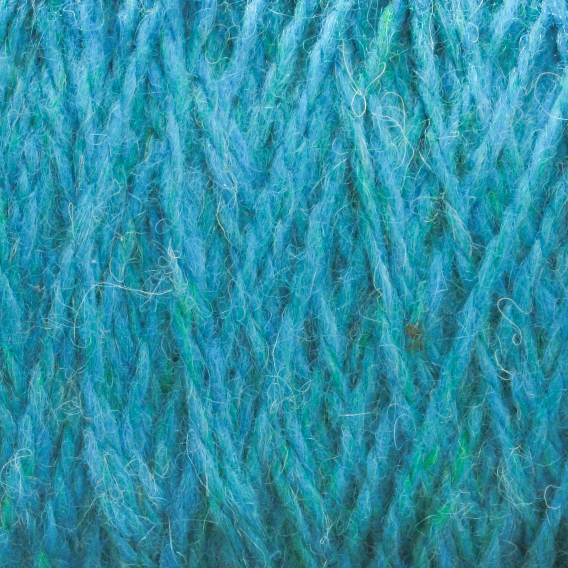 Close-up image of turquoise blue Harrisville Designs Harrisville Shetland Yarn - Unwashed Cones, showing the interwoven strands and fibers in detail. The yarn has a fluffy and slightly fuzzy texture, with visible threads and a mix of light and dark blue shades—perfect for lightweight blankets or Fair Isle knitting designs.