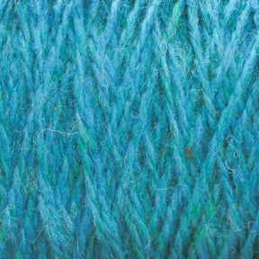 Close-up image of turquoise blue Harrisville Designs Harrisville Shetland Yarn - Unwashed Cones, showing the interwoven strands and fibers in detail. The yarn has a fluffy and slightly fuzzy texture, with visible threads and a mix of light and dark blue shades—perfect for lightweight blankets or Fair Isle knitting designs.