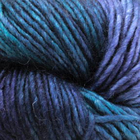 Close-up of a skein of Malabrigo Silky Merino yarn by Malabrigo Yarn, featuring a blend of deep blue and purple hues. The fibers are tightly wound, showcasing both the smooth texture and subtle changes in color throughout the luxury merino yarn.