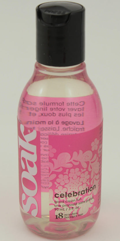 A 90mL, clear plastic bottle of Soak Wash, a delicate wash liquid laundry detergent from Soak Wash Inc. The bottle contains a pink liquid and is adorned with decorative floral patterns along with the words "celebration" and "pure clean fun" on its label. It features a black flip-top cap and is biodegradable.