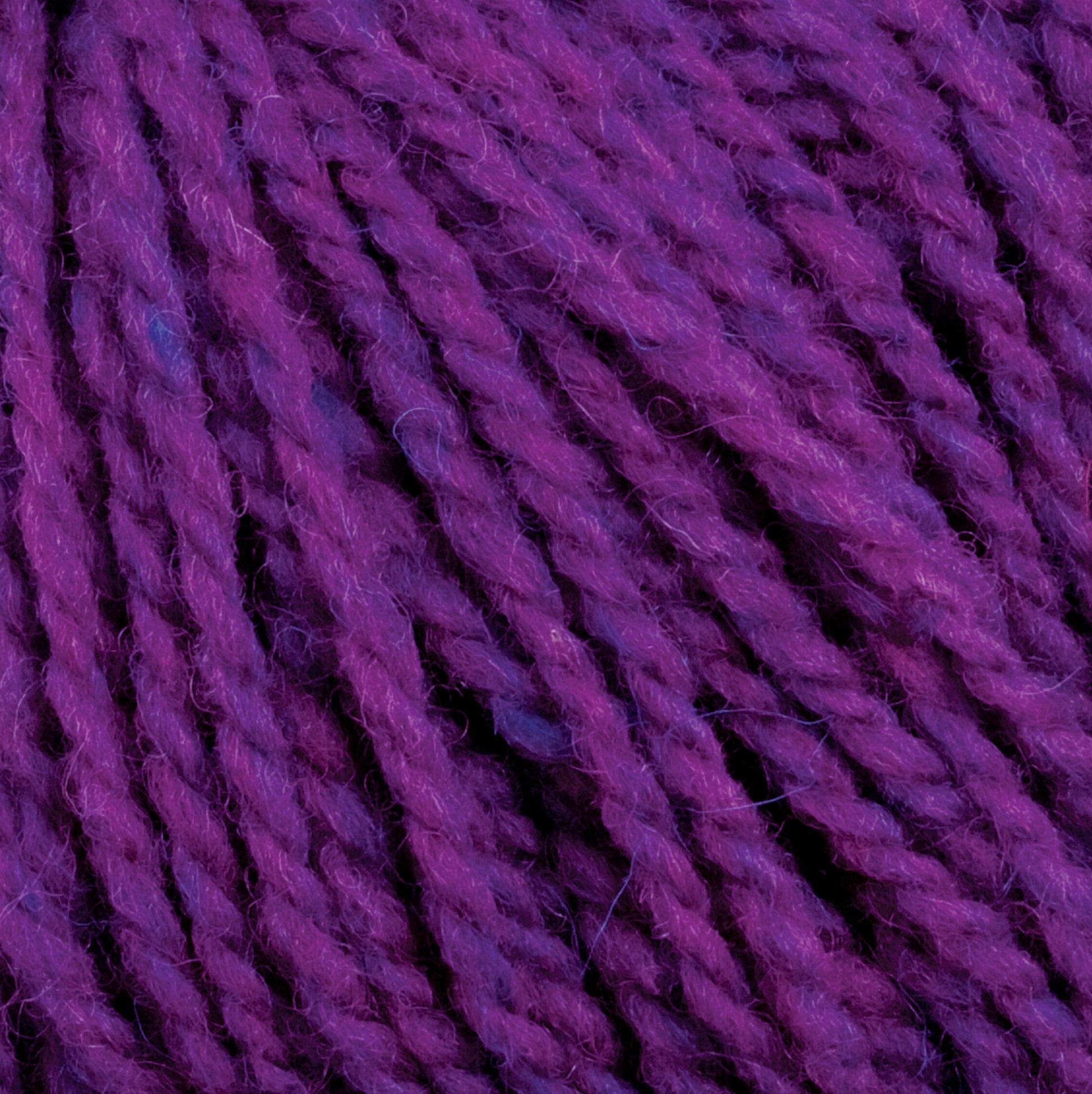 Close-up image of Harrisville Highland - Cones by Harrisville Designs. The unscoured purple yarn strands, infused with spinning oils, are tightly twisted, showcasing varying shades of purple that add depth and texture.