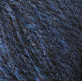 Close-up image of a mass of Harrisville Designs Peace Fleece Yarn, featuring varying shades of dark and light blue. The texture appears soft and slightly fuzzy, showcasing the intertwined fibers and overall thickness of this wool and mohair blend.