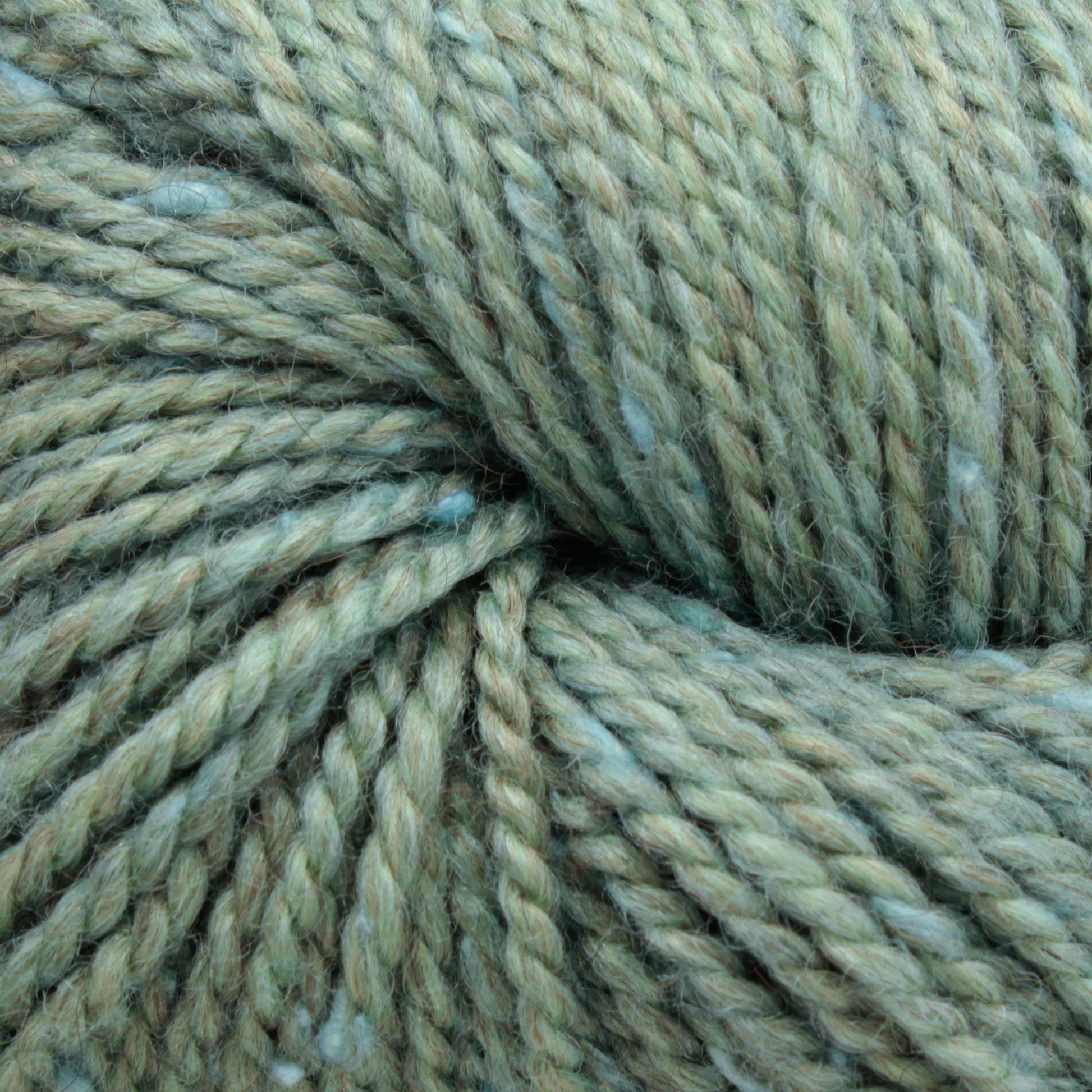 A close-up image of Acadia by The Fibre Co. (UK) Ltd in sage green with hints of blue. The twisted strands are tightly wound together, showcasing the yarn's texture and slight variations in color, reminiscent of natural scenic beauty.