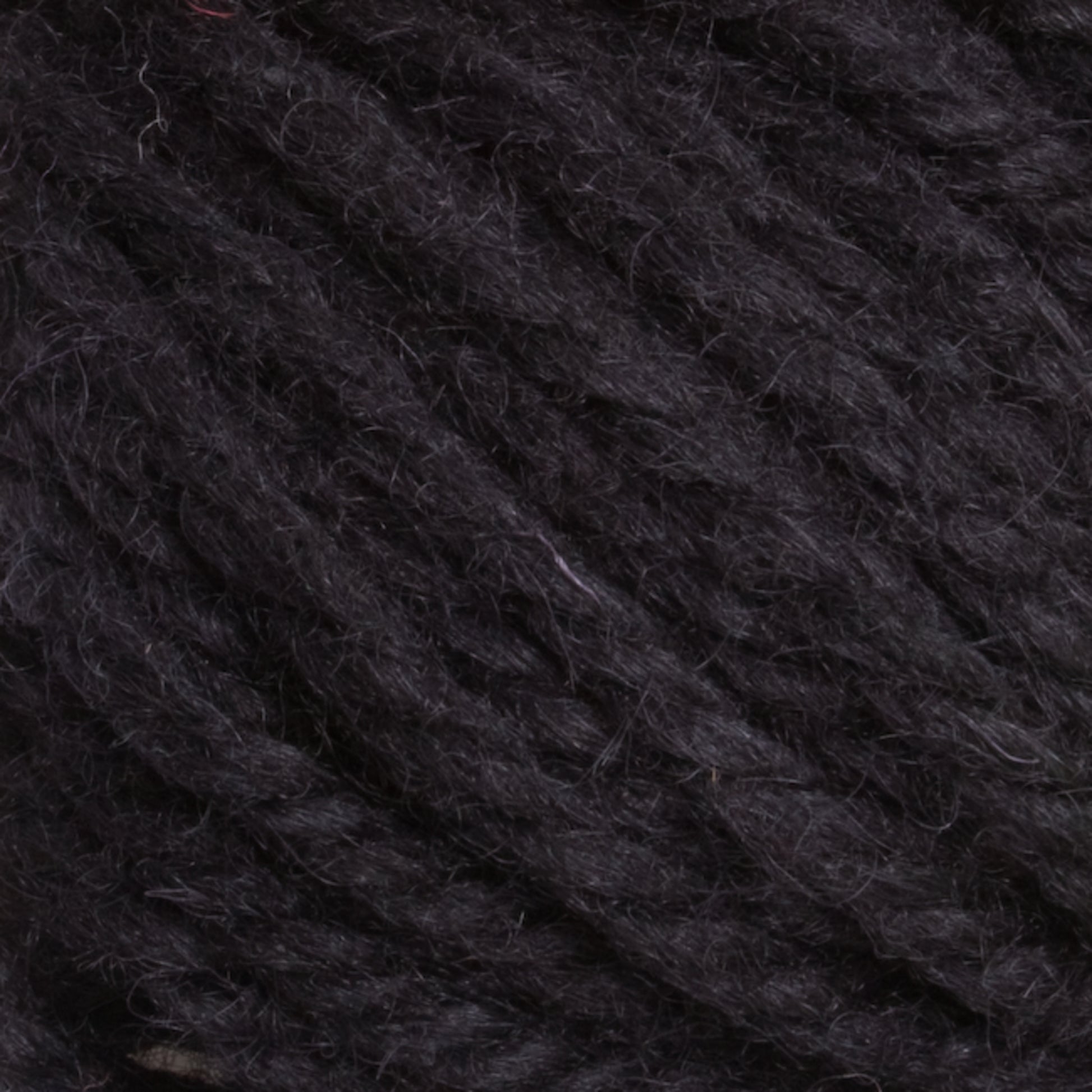 A close-up view of dark, thick Halcyon Yarn Classic Rug Wool | Strand by Caledonian Dye Works. The fibers are tightly twisted together, showcasing a textured and slightly fuzzy surface with subtle variations in shade. The overall color is a deep black with hints of dark gray, making it perfect for discerning rug weavers.