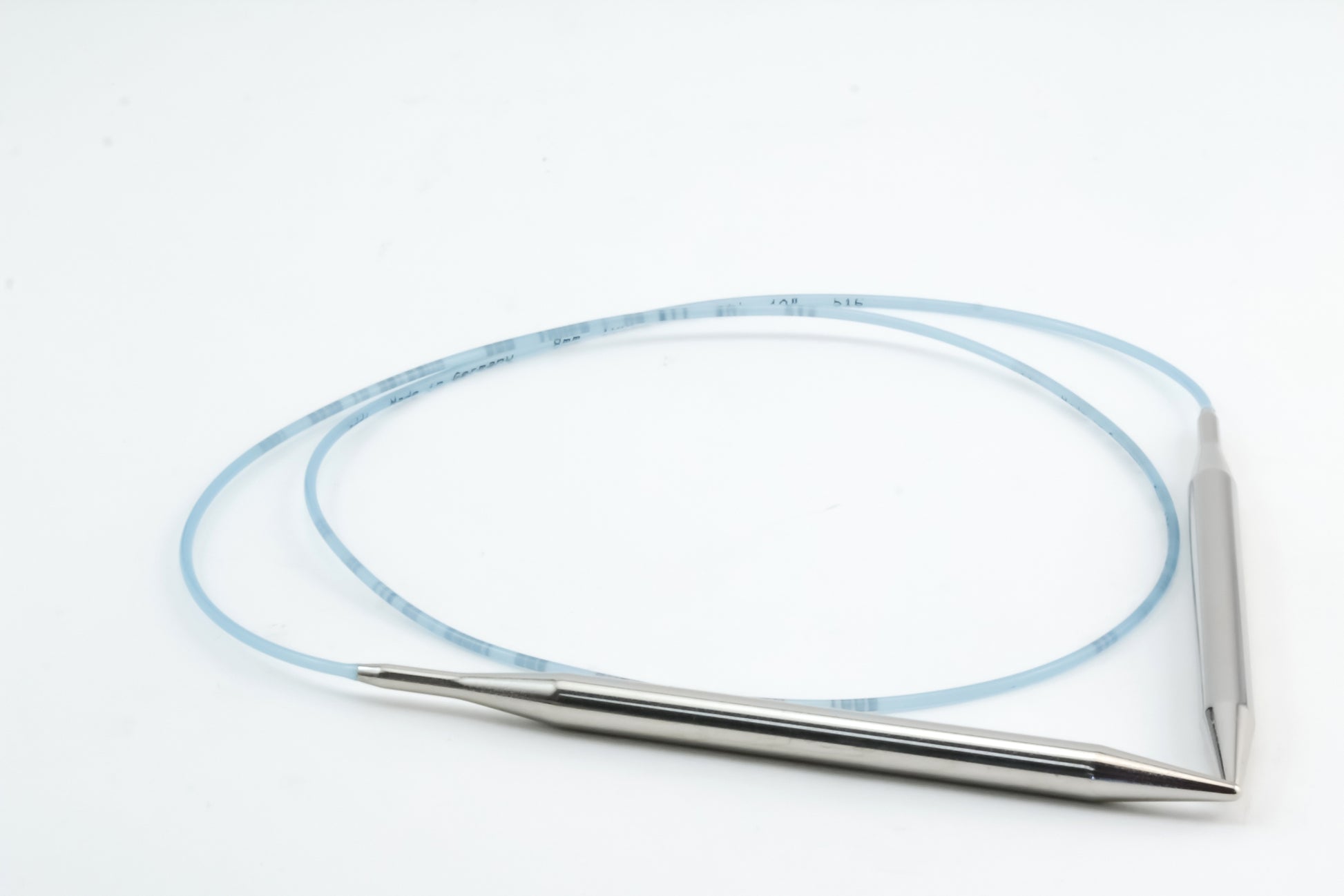 A flexible, thin, and translucent blue silicone tube with sleek metallic tips on both ends is arranged in a loose loop on a white background. Reminiscent of Addi Turbo Circular Knitting Needles from Skacel, the metallic tips are cylindrical and create a sharp contrast with the pliable tube.