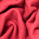 A close-up of Europa Wools Ltd's Merino Prefelt, showcasing its vibrant red color and soft, textured surface with folds and creases that add depth and warmth. Ideal for nuno felting projects, this cozy woolen fabric highlights both comfort and texture.