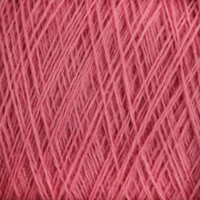 Close-up image of a ball of pink JaggerSpun Maine Line 2/20 Yarn | Large Cone. The yarn, produced by Jagger Brothers, Inc., is intricately wound, with various strands crossing over each other, creating a textured and layered appearance. The medium-grade wool fibers appear soft and slightly fuzzy.