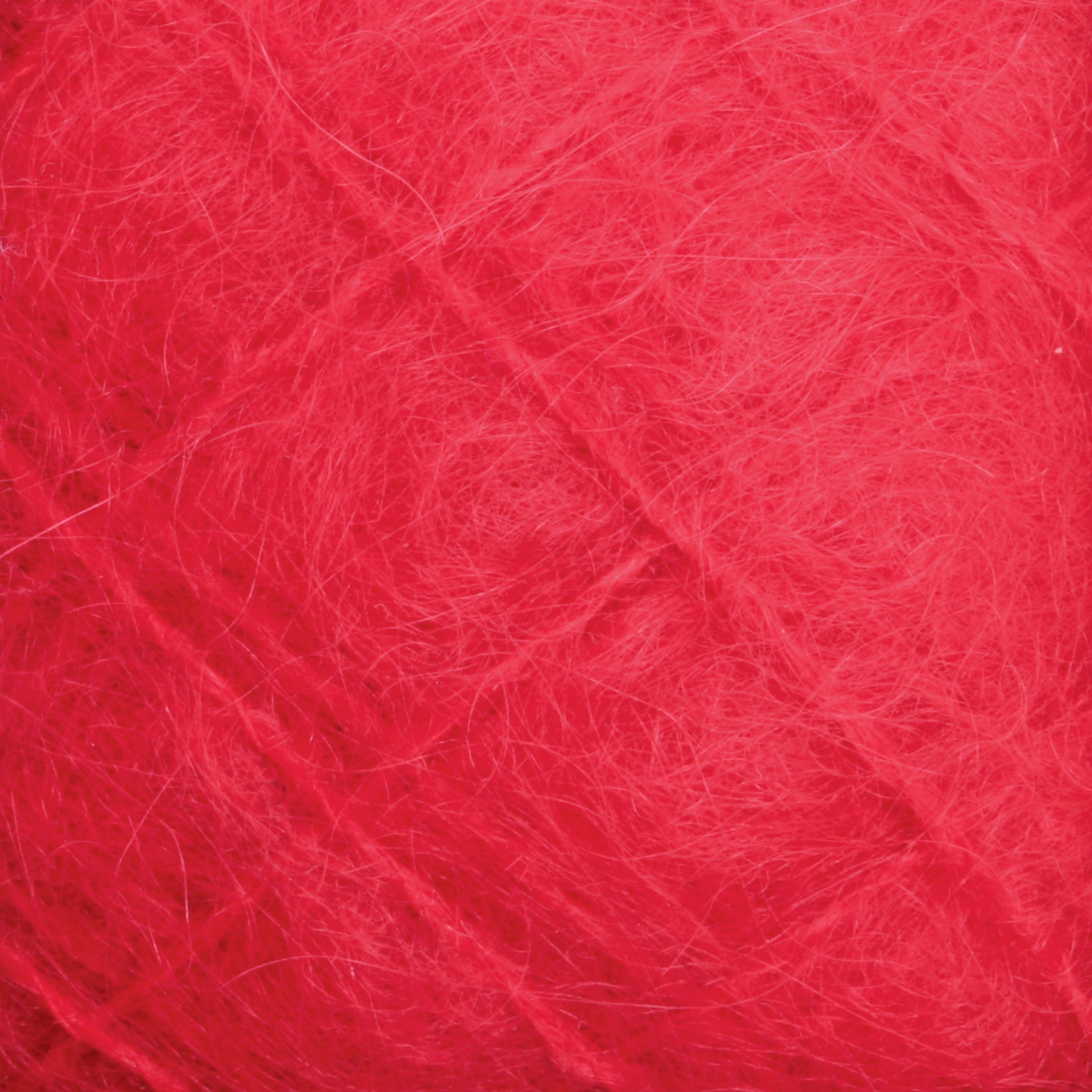 Close-up of the Victorian Brushed Mohair Yarn | Large Skein by Caledonian Dye Works. The soft, fluffy fibers are intricately intertwined, creating a dense and slightly fuzzy texture in varying shades of red, evoking the charm of classic Victorian yarns.