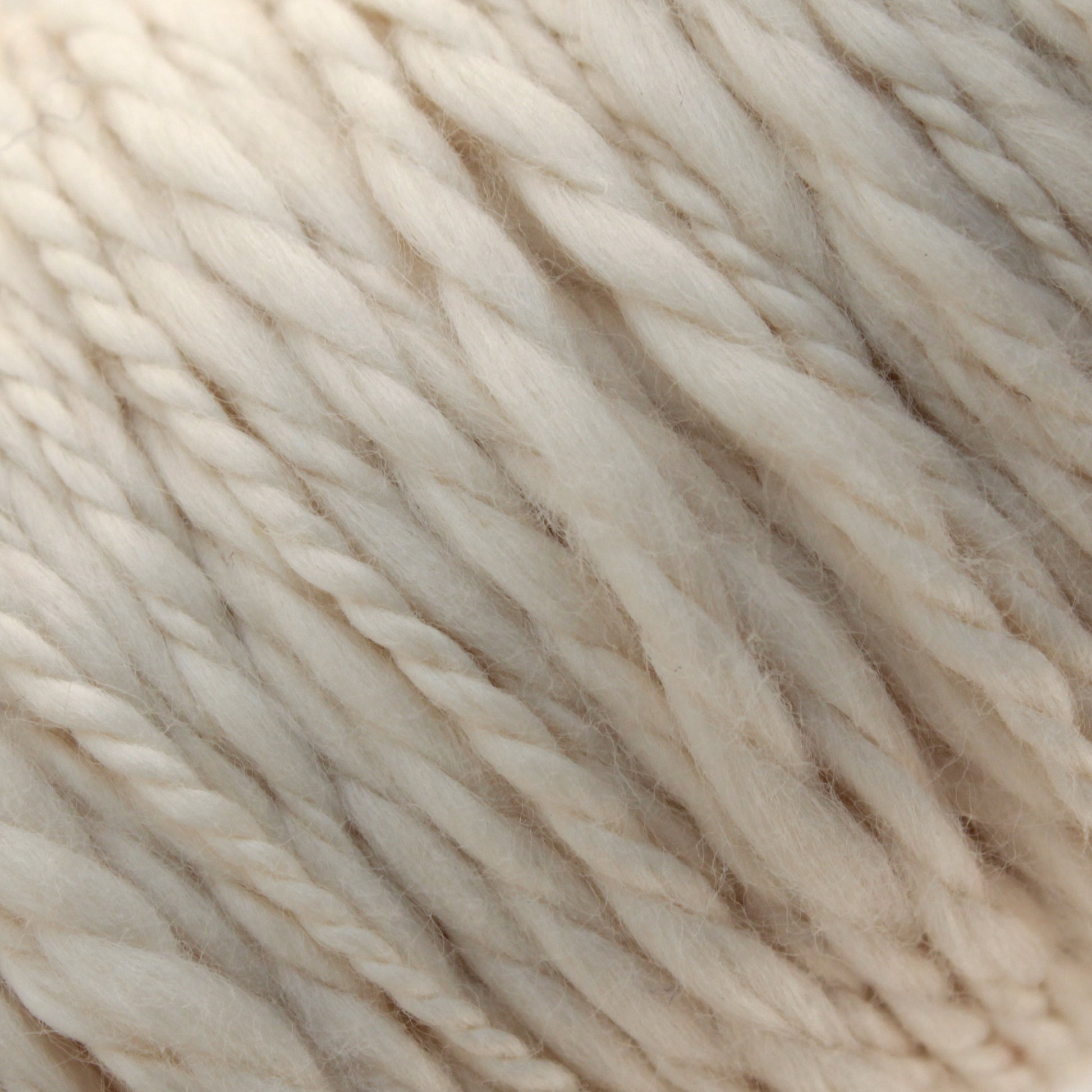 Close-up of Henry's Attic Inca Organic Cotton yarn, showcasing its soft and slightly fluffy texture with twisted fibers. The image highlights the intricate details and natural hues of the yarn, making it ideal for weaving projects and crafting.