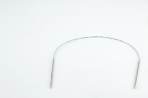 An image depicting a thin, flexible, translucent medical catheter with two metallic ends resting on a plain white surface. The catheter is gently curved and features markings along its length, evoking the precision of Skacel's Addi Turbo Circular Knitting Needles used for crafting intricate doll clothes.