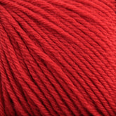 Close-up image of a ball of Baby Blatt by Anny Blatt yarn from Essentially Felt Studio & Fine Yarn. The texture is soft and fibrous, with multiple strands twisted together. The color is a vibrant, rich red, and the image captures the detailed weave of the machine-washable fibers in this fingering-weight baby yarn.