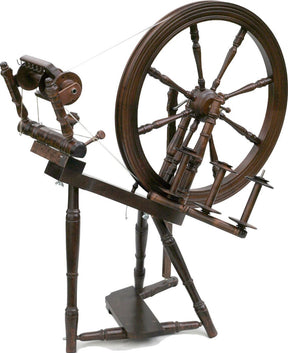 The Kromski Interlude Spinning Wheel from Kromski North America is a vintage piece crafted from European alder and birch. It features a large wheel connected by a drive band to smaller components, showcasing intricate craftsmanship with its single drive angle treadle and multiple spindles, perfect for spinning fibers into yarn while reflecting historical design.