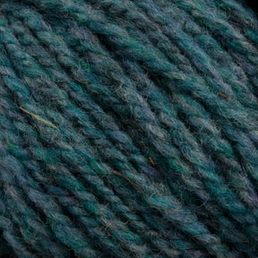 Close-up of thick, multi-toned Tuffy Canadian Sock Yarn by Briggs & Little in shades of teal and green. This worsted weight yarn has a slightly fuzzy texture, with tightly twisted strands that create a rich, textured pattern perfect for cozy winter socks.