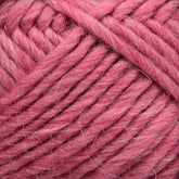 Close-up image of a ball of Lamb's Pride Bulky Yarn from Brown Sheep, showcasing thick, pink strands with a visible texture of intertwined and soft woolen threads, ideal for knitters and crocheters crafting cozy Icelandic sweaters.