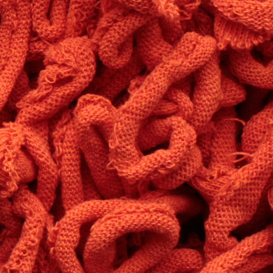 Close-up image of a textured, tangled mass of bright orange cotton loops from the Harrisville Potholder Loops - Traditional Size Mini Pack by Friendly Loom. The loops intertwine and overlap, creating a dense, intricate pattern reminiscent of those made on a traditional potholder loom.