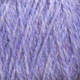 Close-up view of a textured ball of Harrisville Designs' Harrisville Shetland Yarn - Unwashed Cones, featuring various shades of purple with hints of blue and pink. The fibers appear soft and fluffy, showcasing a twisted and intertwined pattern that is ideal for Fair Isle knitting designs.