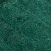 Close-up image of green Victorian Brushed Mohair Yarn fibers interwoven together, creating a soft and fuzzy texture. This luxurious yarn from Caledonian Dye Works appears fluffy and dense, ideal for knitting or crochet projects. The rich green color enhances the yarn's vibrant and cozy feel, reminiscent of classic Victorian textiles.