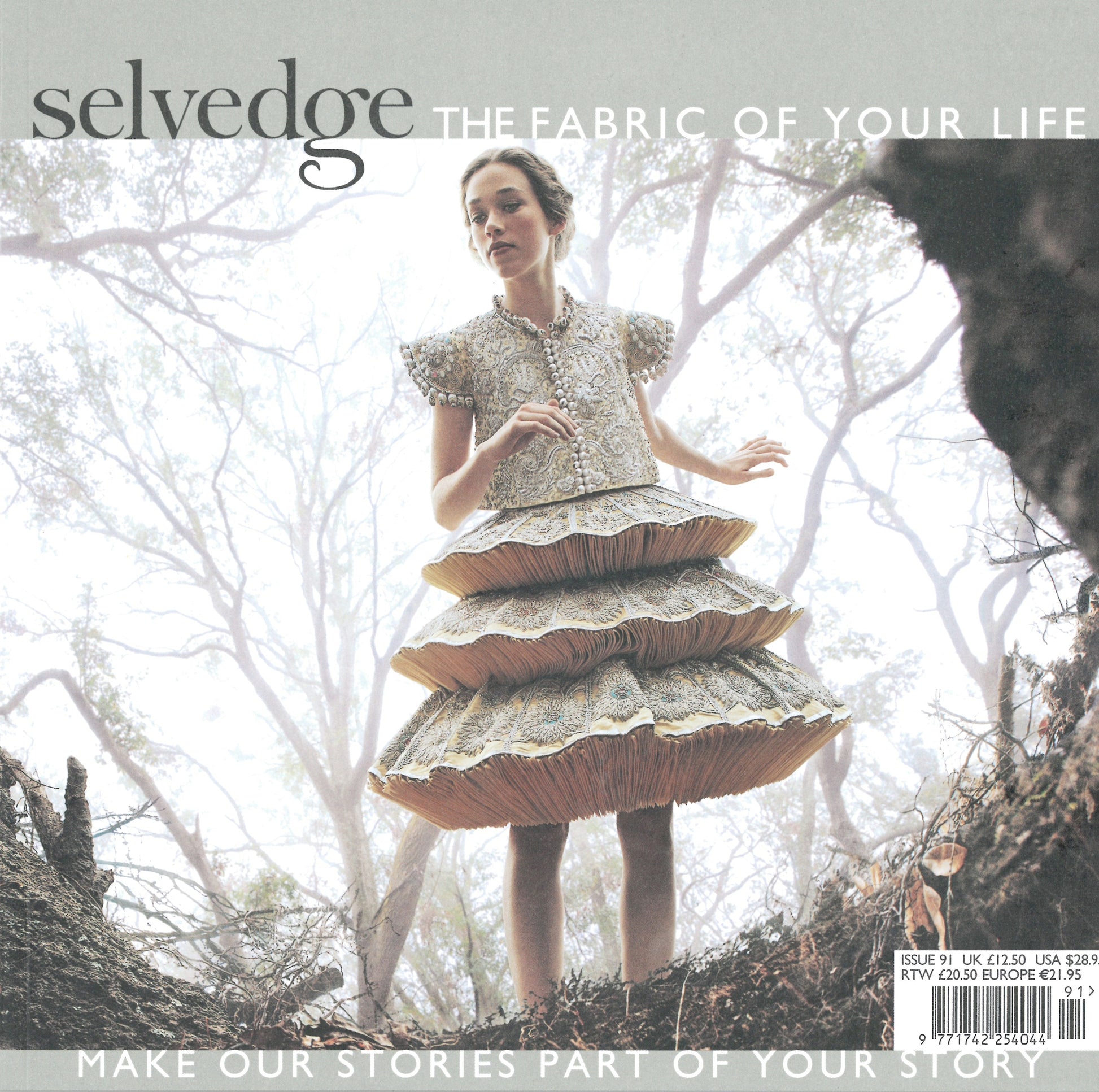 A woman stands outdoors, wearing a multi-layered, intricately designed dress. The text on the image reads "Selvedge - Issue 91: Luxe," celebrating the beauty of artisanal textiles by Selvedge. Trees and sky are visible in the background, and the lower text reads "Make our stories part of your story.