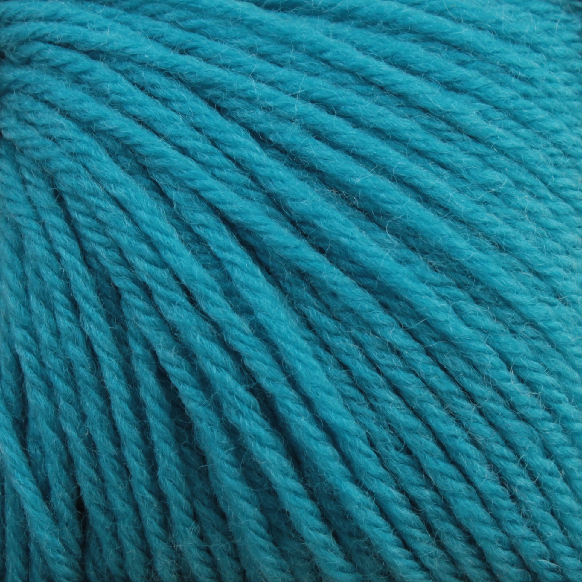 Close-up of a bundle of turquoise Baby Blatt by Anny Blatt yarn from Essentially Felt Studio & Fine Yarn, displaying tightly wound strands. The texture is soft and slightly fuzzy, and the vibrant color stands out prominently. This fingering weight yarn is perfect for delicate projects and is conveniently machine washable.