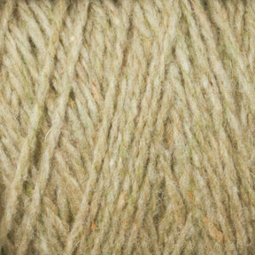 Close-up of Harrisville Designs' Harrisville Highland - Cones in beige, showcasing subtle green accents and the texture and twist of the fibers. The slightly fuzzy and soft unscoured yarn hints at possible knitting or crocheting uses. The intricate details of the threads are highly visible.