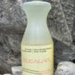 A 16.9 oz bottle of Eucalan Wool Wash, enriched with lanolin, is placed on a rocky surface. The translucent bottle contains a yellowish solution and features a green round cap and beige labeling in both English and French. This 100% biodegradable concentrate from Eucalan promises gentle care for your finest fabrics.