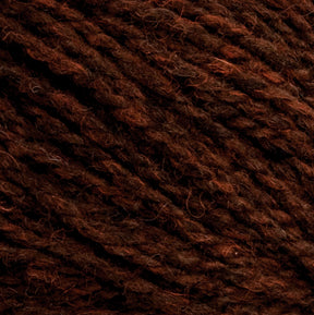 Close-up image of dark, textured yarn in shades of brown and deep red, emphasizing the intertwined fibers and natural, earthy appearance. The intricate detail showcases the thickness and color variation of Harrisville Designs' Harrisville Highland - Cones yarn.