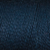 Close-up of a spool of Maurice Brassard's 8/2 Bamboo Yarn Mini-cone in dark blue. The eco-friendly bamboo yarn showcases its texture with tightly wound fibers and subtle variations in color and thickness. Smooth with faint specks of lighter blue interspersed, it's ideal for knitters seeking sustainable options.