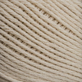 Close-up image of Brown Sheep's Cotton Fleece yarn in a beige hue, wound into a ball. The texture of the cotton fibers is distinctly visible, highlighting the tightly twisted strands and creating a consistent pattern of parallel lines. The soft pastels accentuate the yarn's intricate detail against an out-of-focus background.