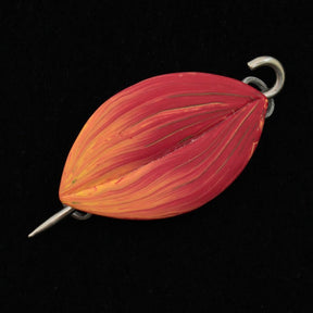 The Hosta Shawl Pin by Bonnie Bishoff Designs, offered by Bonnie Bishoff, is elegantly shaped like an elongated leaf and painted in a stunning gradient of red and yellow hues. Crafted from polymer clay, it features a metal loop at one end and a pointed hook at the other. The vivid colors of the pin stand out beautifully against a black background.