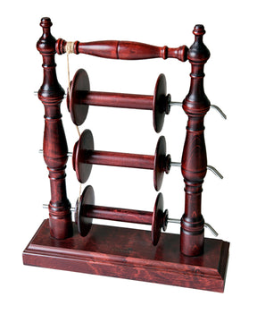 The Kromski Lazy Kate Arch by Kromski North America is a wooden spool holder with a dark stain finish, designed to hold six spools. It features two vertical columns on either side with intricate carvings, connected by three horizontal bars with tension control for ply yarn, standing on a rectangular base.