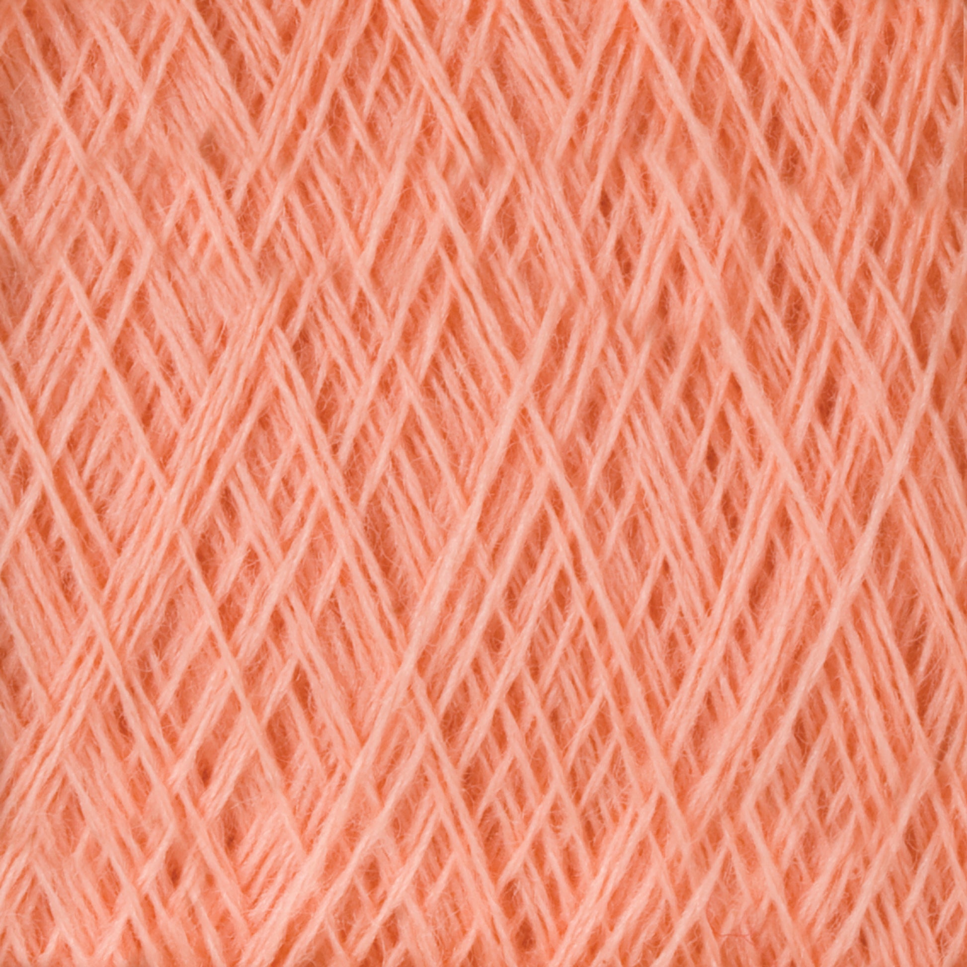 Close-up image of a spool of Jagger Brothers, Inc.'s JaggerSpun Maine Line 2/20 Yarn | Large Cone, showcasing a peach-colored hue. The medium-grade wool is tightly wound, highlighting its soft and fibrous texture. The yarn strands create a crisscross pattern throughout the image.