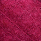 Close-up image of fuzzy, deep pink yarn with visible fibers and strands. The texture appears soft and slightly tangled, highlighting the fine details of the luxurious Victorian Brushed Mohair Yarn from Caledonian Dye Works.